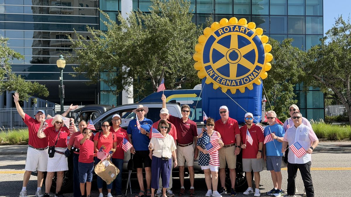 Rotarians waving flags beside a giant inflatable Rotary wheel